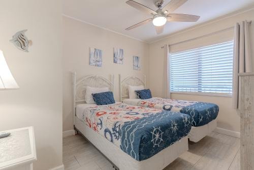 Third bedroom two twin beds window overlooking in a coastal flatscreen TV
